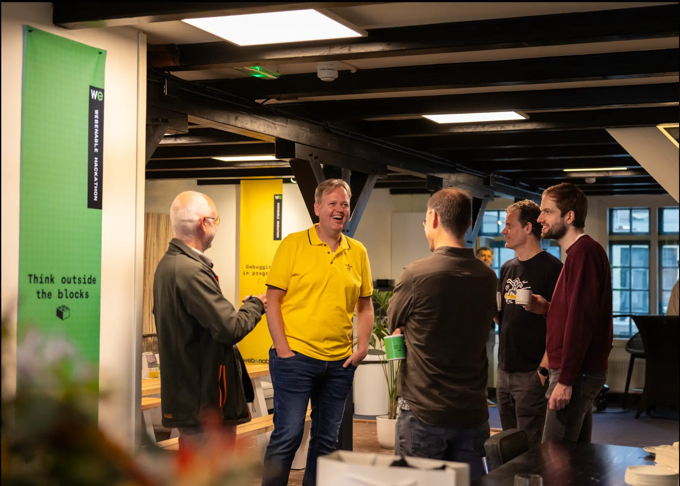 Groepje collega's staat lachend met elkaar te praten tijdens de hackathon